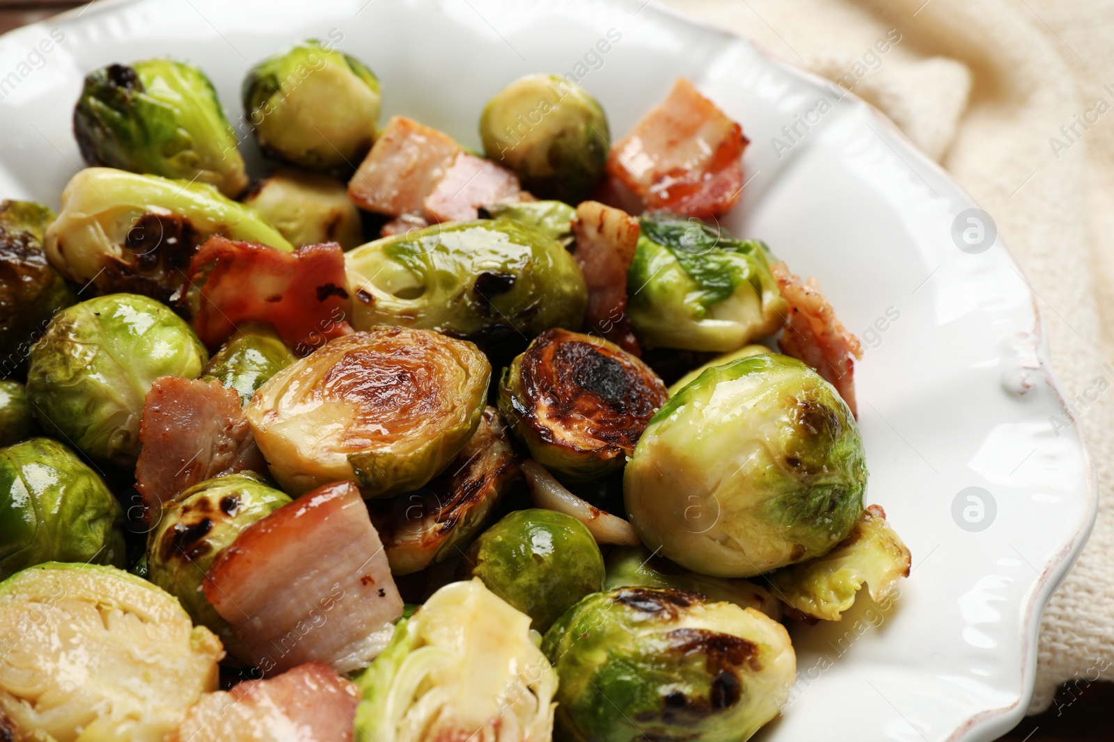 Photo of Delicious Brussels sprouts with bacon in plate, closeup