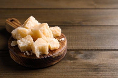 Pieces of delicious parmesan cheese on wooden table. Space for text