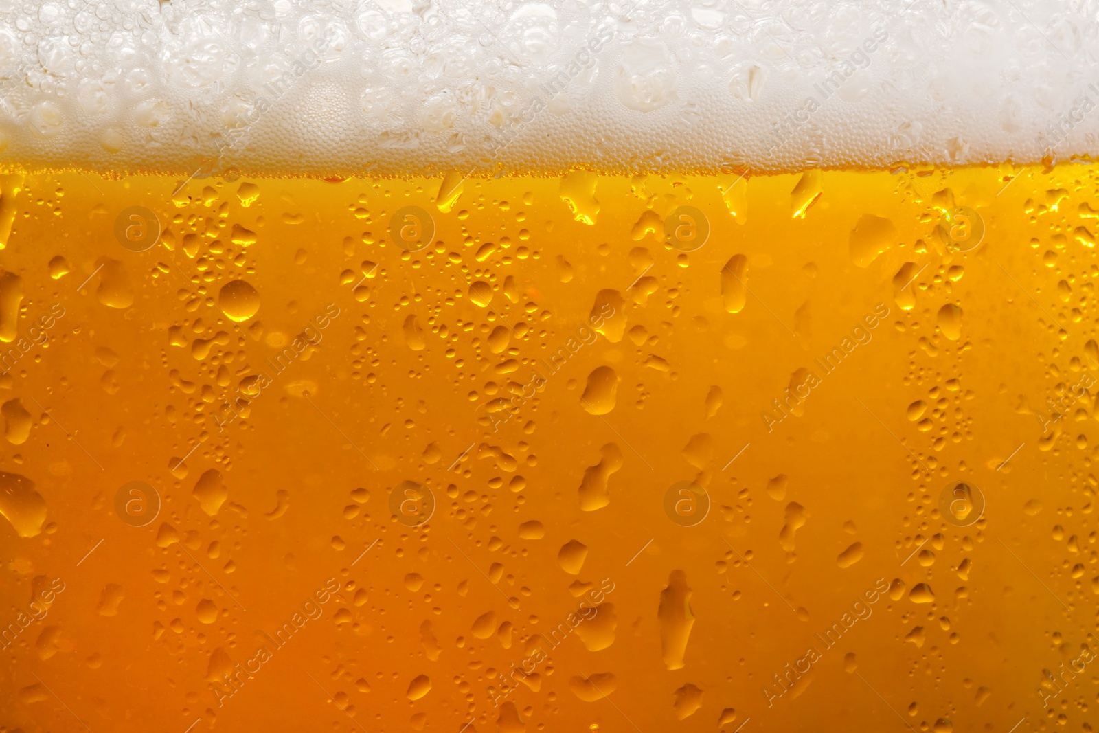 Photo of Glass of tasty cold beer with foam and condensation drops as background, closeup