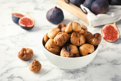 Photo of Bowl with delicious dried figs on marble table. Organic snack