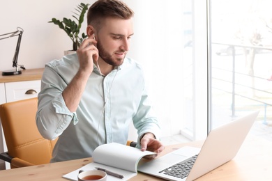 Photo of Young man working with laptop at desk. Home office