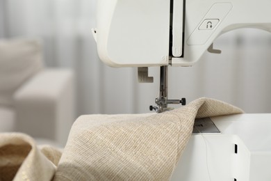 Photo of White sewing machine and fabric on blurred background, closeup