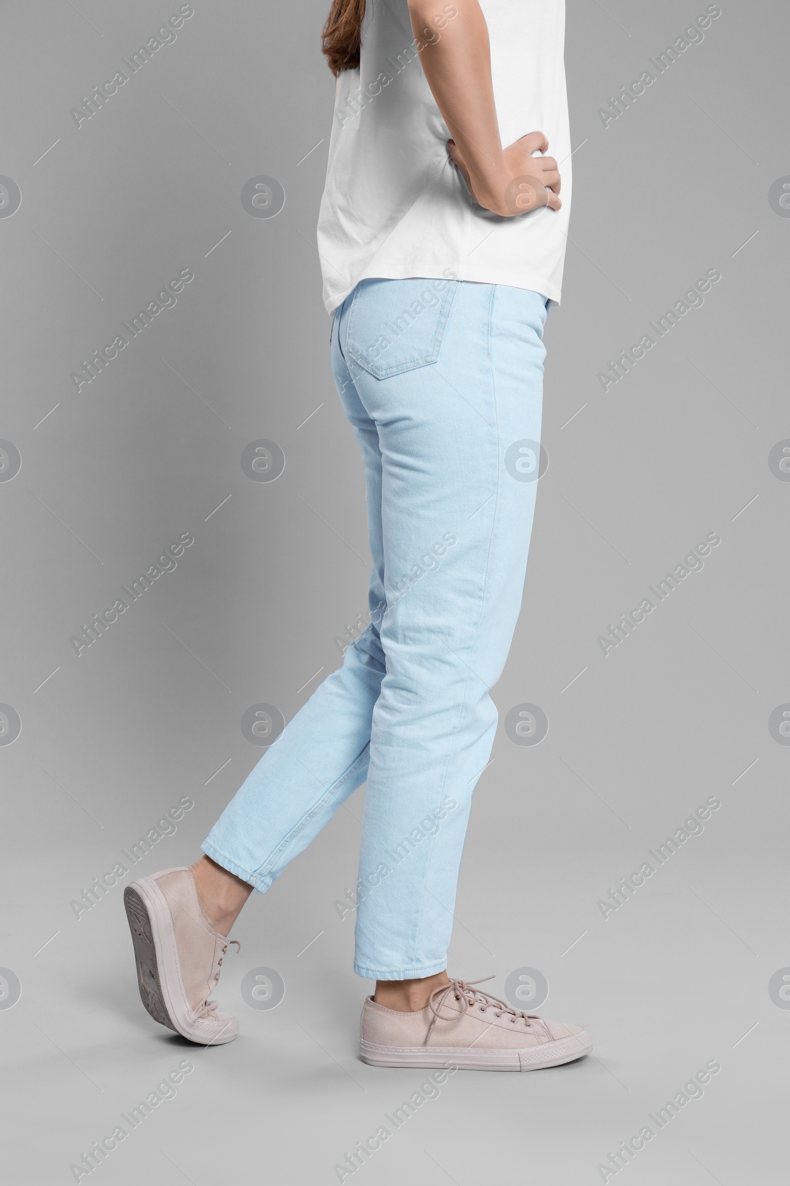 Photo of Young woman in stylish jeans on grey background, closeup