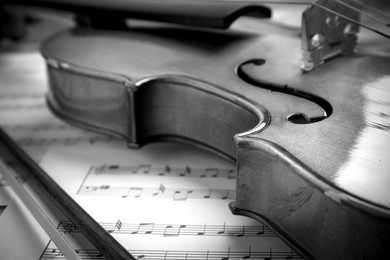 Image of Beautiful violin, bow and note sheets, closeup. Black and white tone