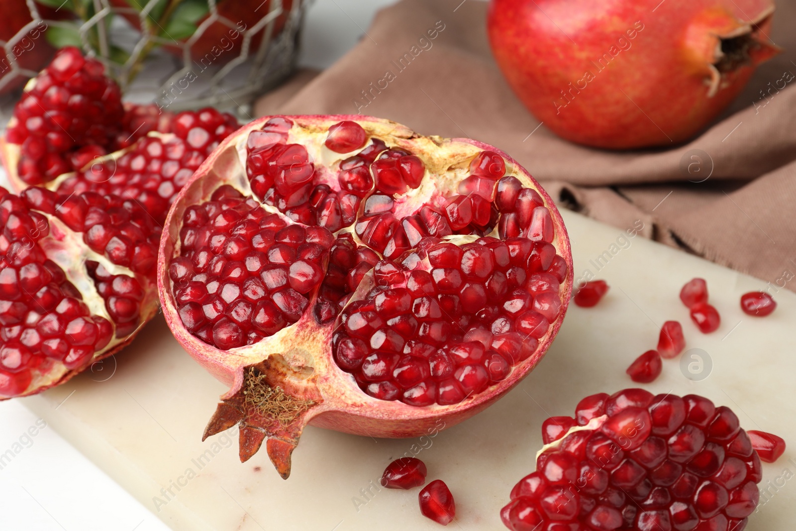 Photo of Piece of fresh pomegranate and seeds on white table, closeup