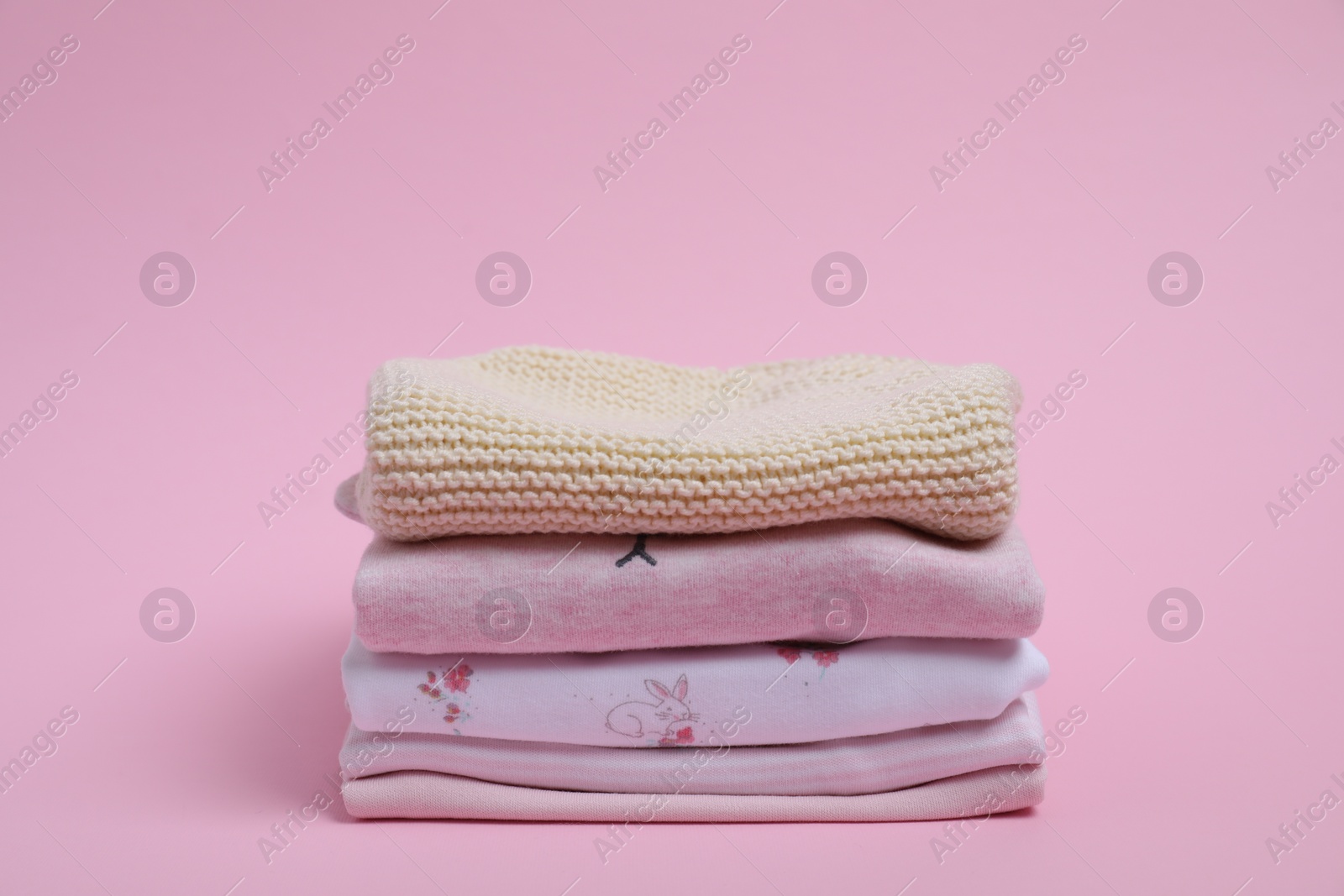 Photo of Stack of clean baby clothes on pink background