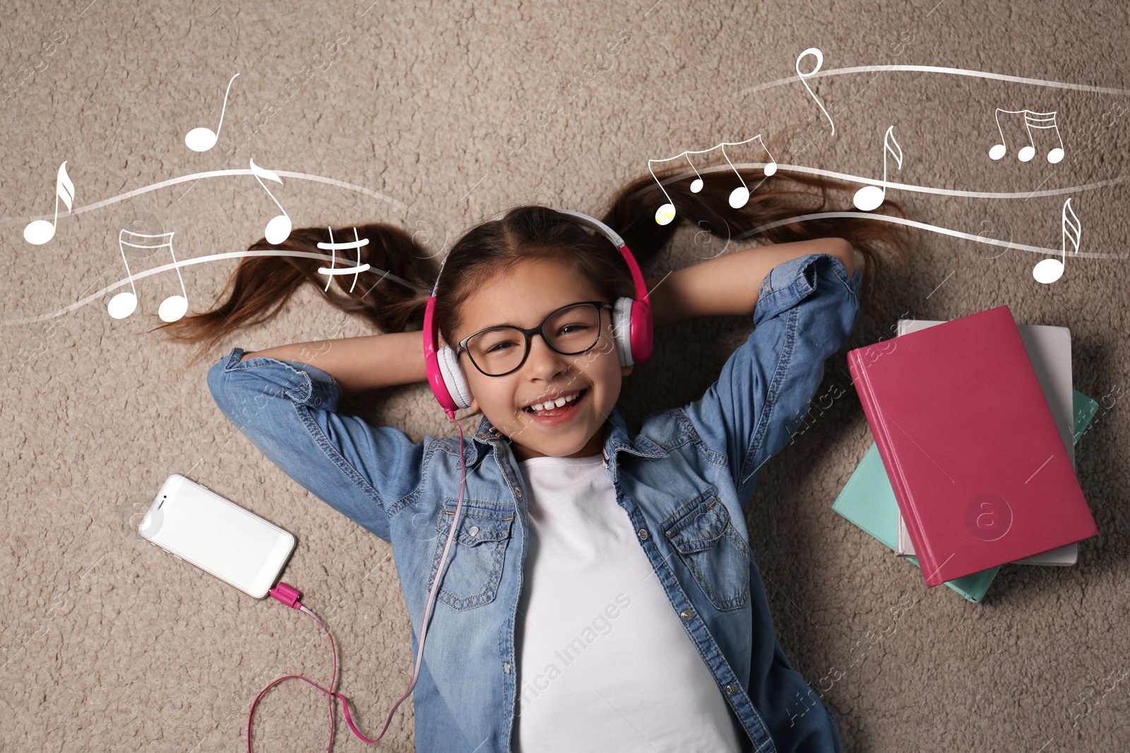 Image of Cute little girl listening to music through headphones on floor, top view