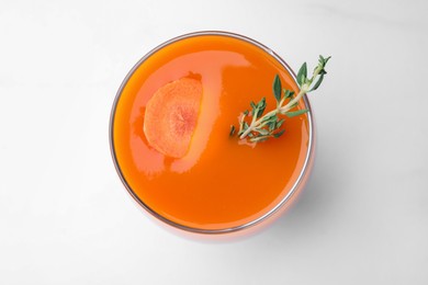 Photo of Glass with healthy carrot juice on white table, top view