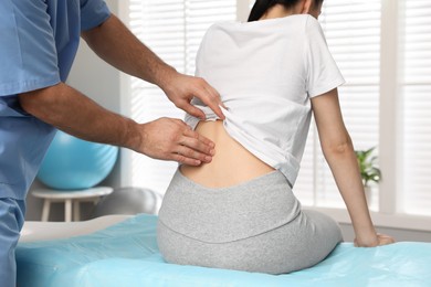 Orthopedist examining woman's back in clinic, closeup. Scoliosis treatment