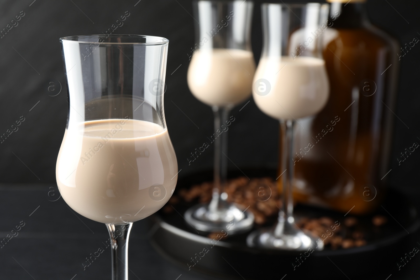 Photo of Coffee cream liqueur in glasses, bottle and beans on table, closeup