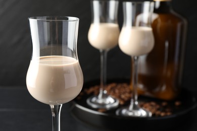 Coffee cream liqueur in glasses, bottle and beans on table, closeup