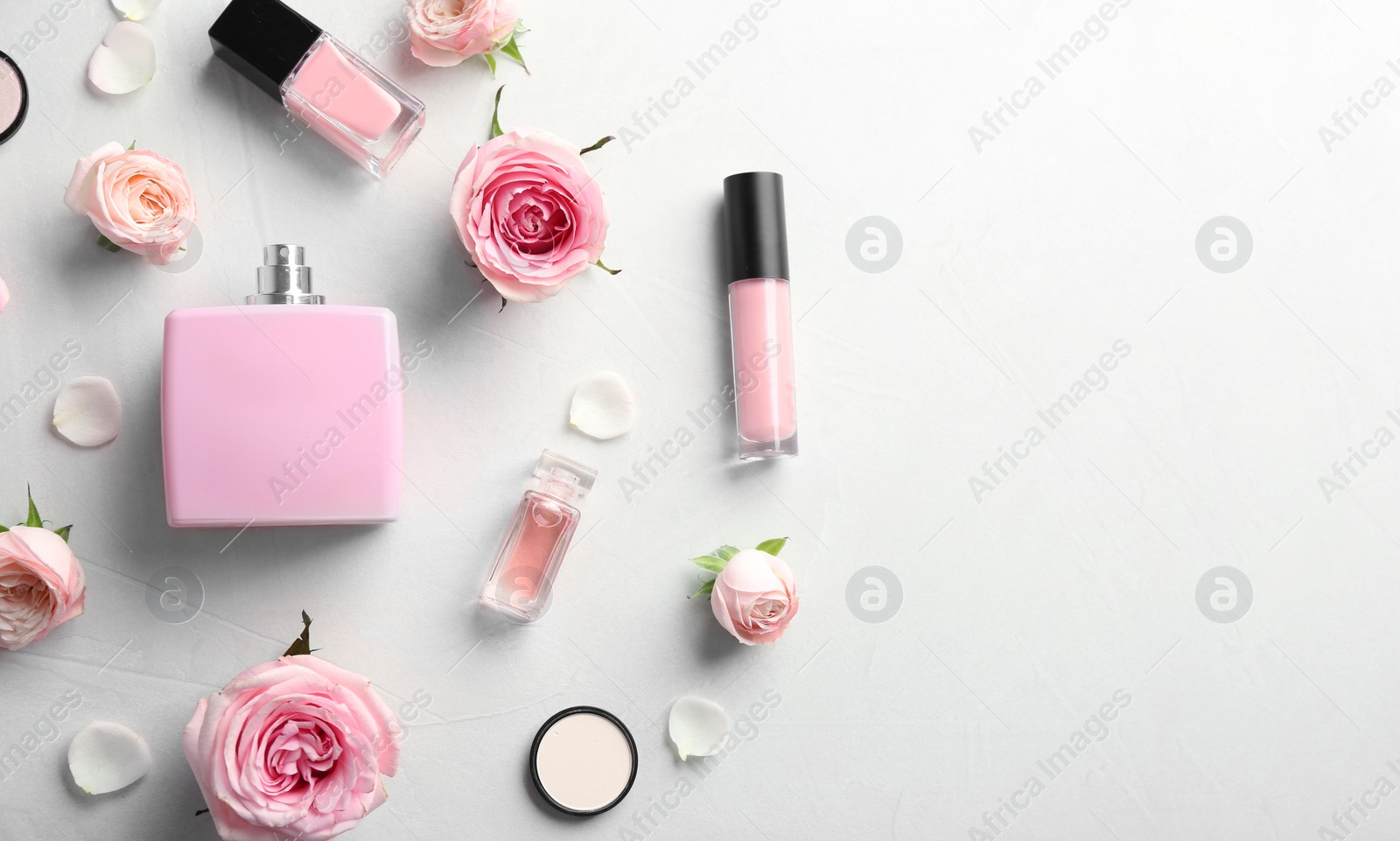 Photo of Flat lay composition with bottles of perfume, cosmetics and roses on grey background. Space for text