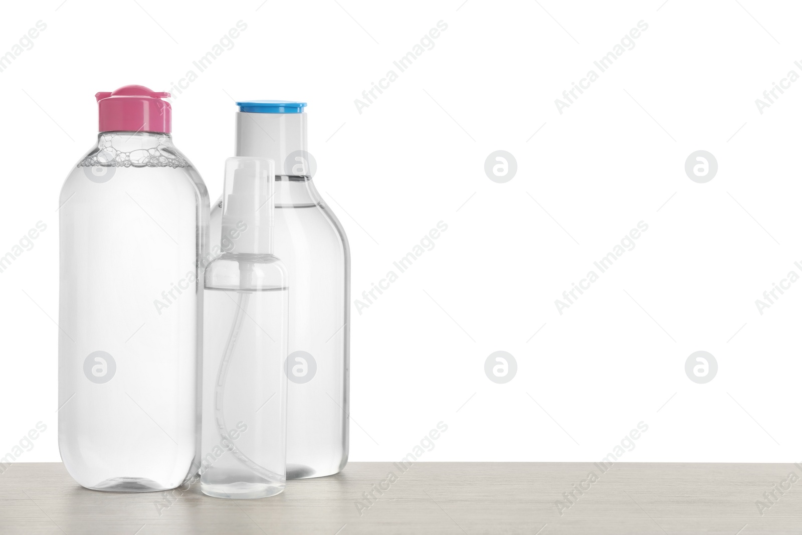 Photo of Micellar water in bottles on table against white background. Space for text