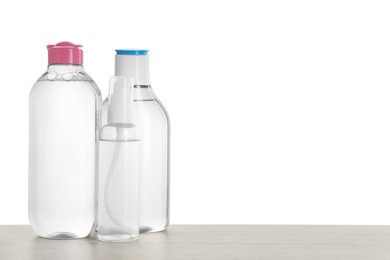 Photo of Micellar water in bottles on table against white background. Space for text