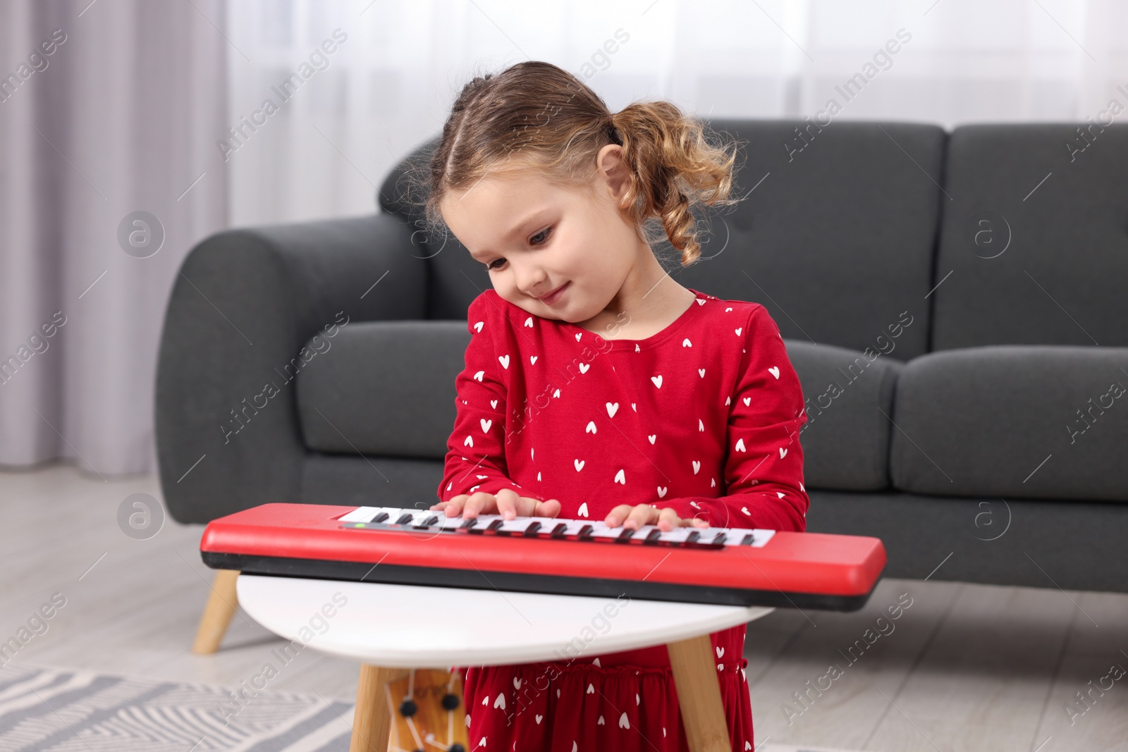 Photo of Little girl playing toy piano at home