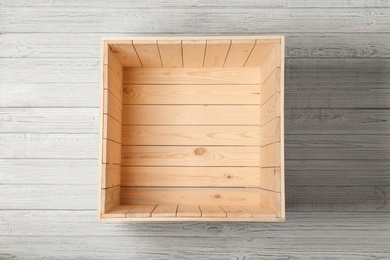 Open empty wooden crate on light background, top view