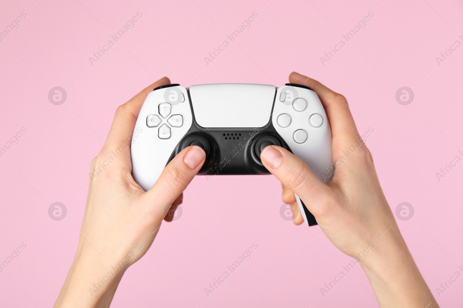 Photo of Woman using game controller on pink background, closeup