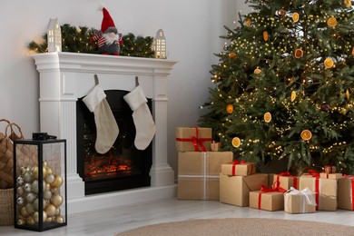 Many different gift boxes under Christmas tree and festive decor in living room
