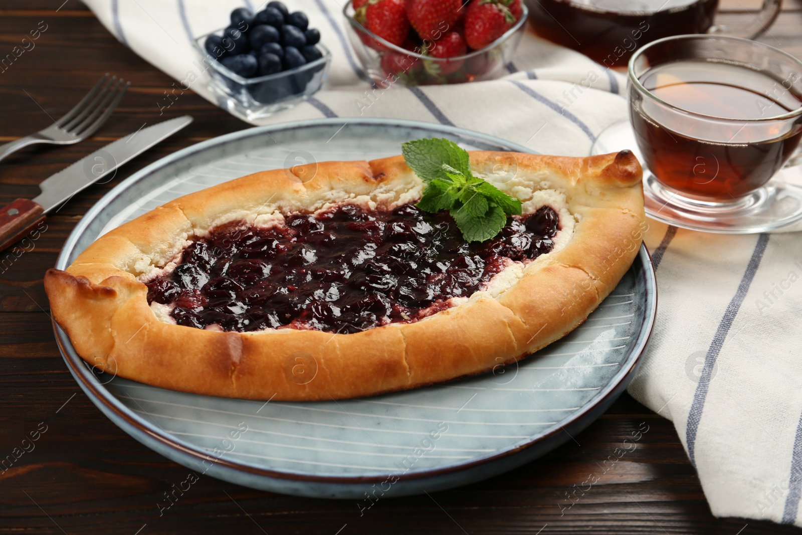 Photo of Delicious sweet cottage cheese pastry with cherry jam served on wooden table