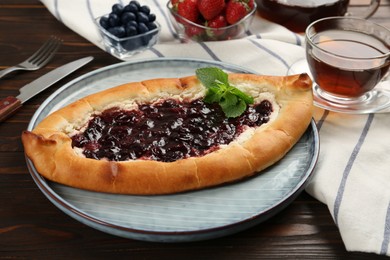 Photo of Delicious sweet cottage cheese pastry with cherry jam served on wooden table