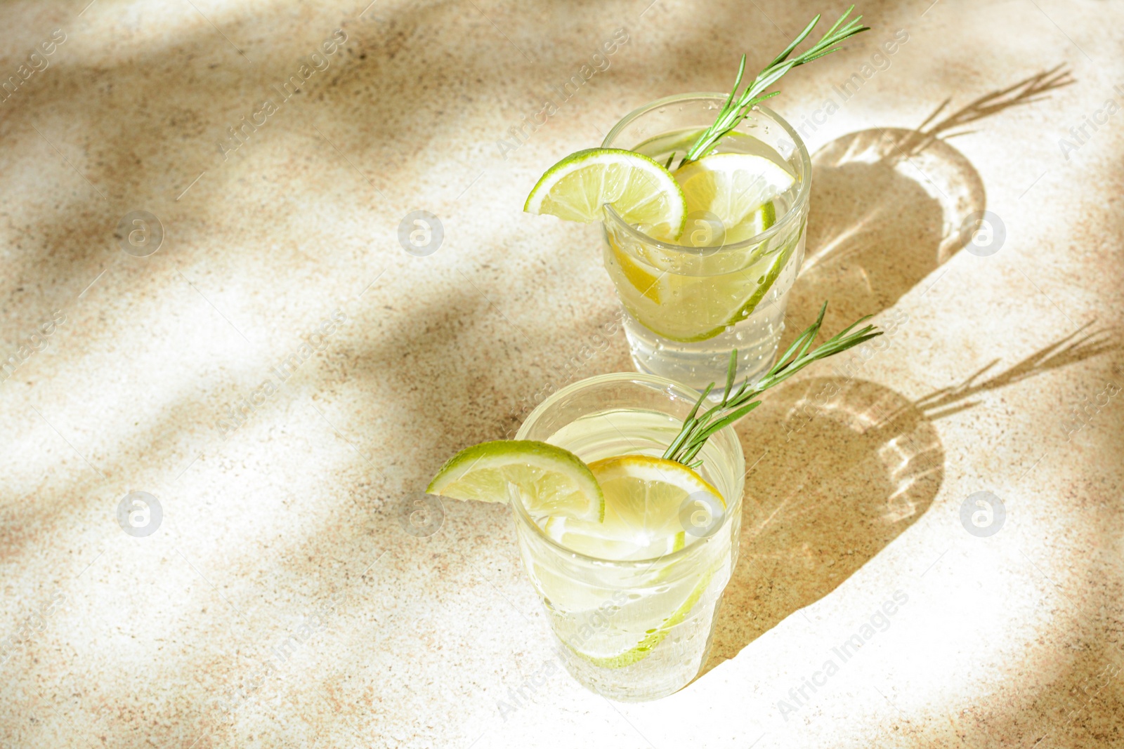 Photo of Glasses of tasty refreshing lemonade on light table, space for text. Summer drink