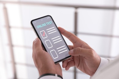 Man using smartphone for online test indoors, closeup