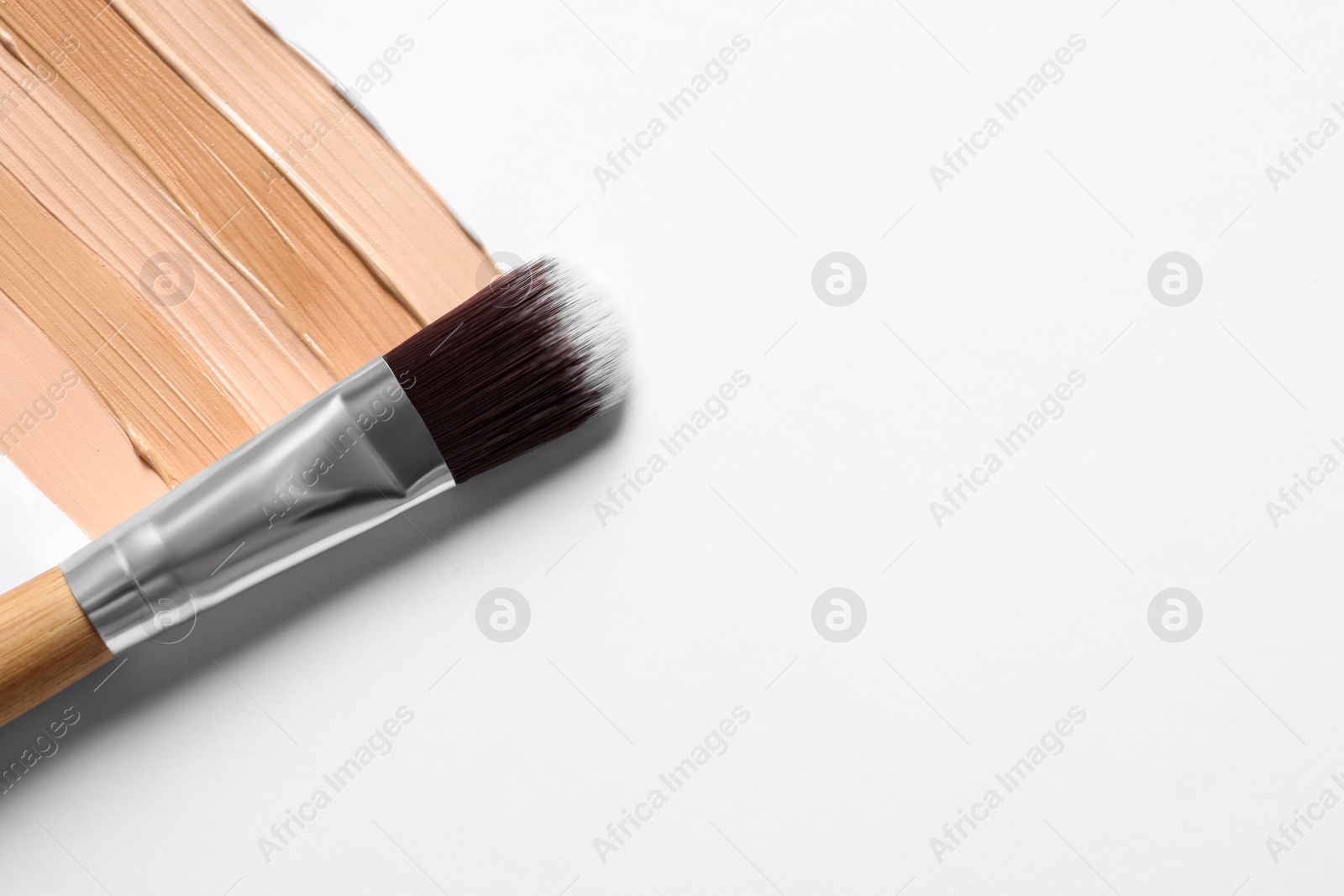 Photo of Samples of skin foundation and makeup brush on white background, top view. Space for text