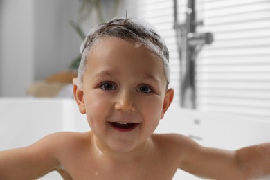 Cute little boy washing hair with shampoo in bathroom, closeup