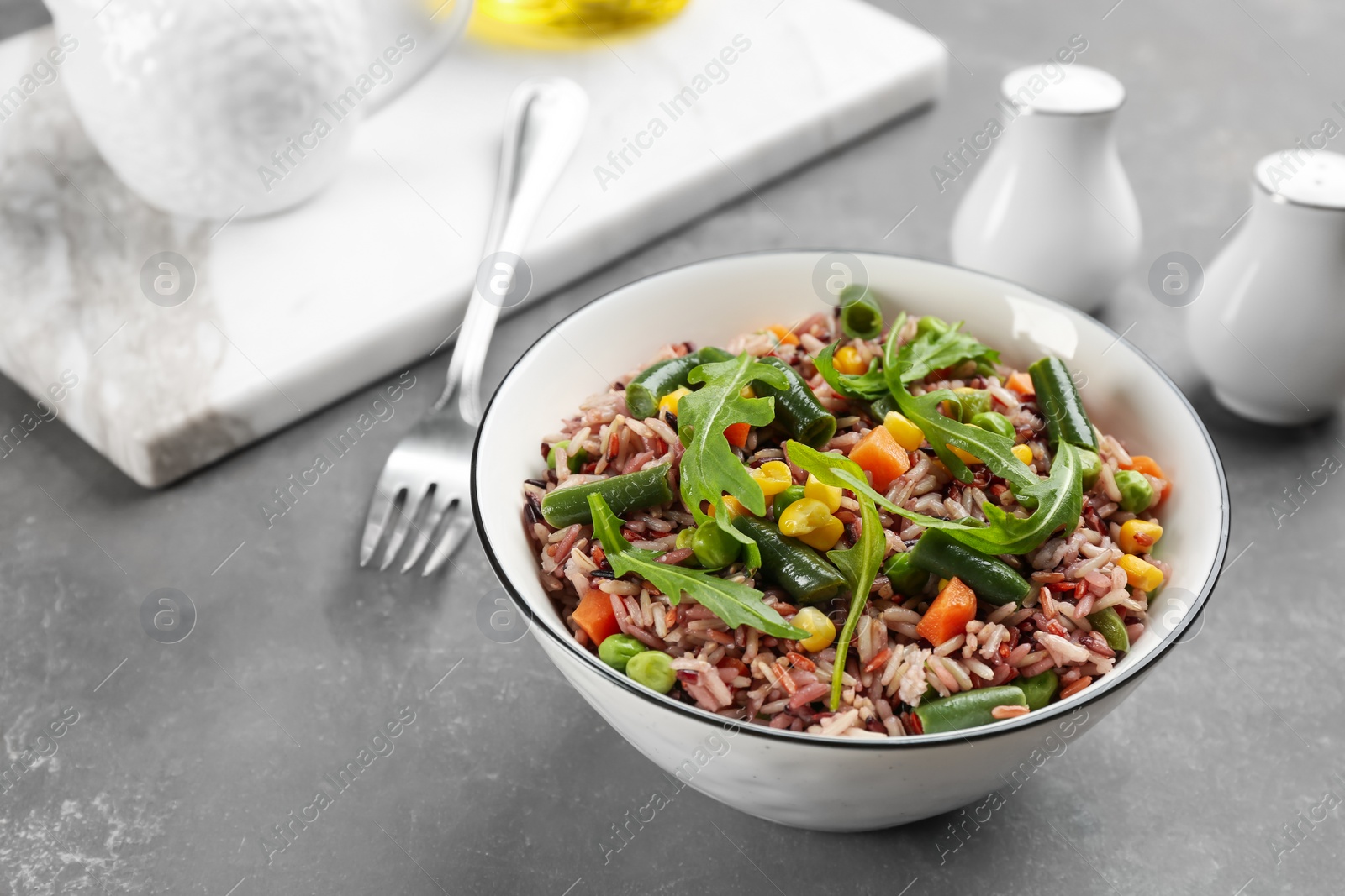 Photo of Tasty brown rice with vegetables on grey table