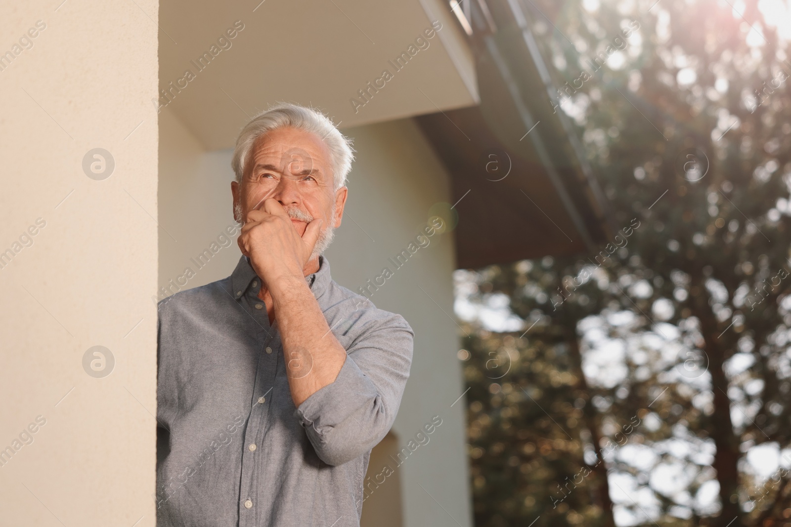 Photo of Portrait of pensive senior man near house outdoors. Annoying neighbour