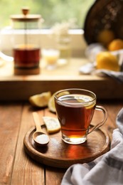 Photo of Glass cup with delicious tea and sugar on wooden table