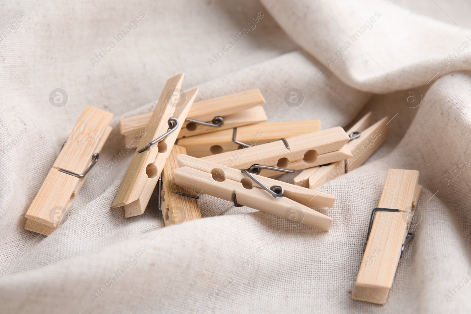 Photo of Pile of wooden clothespins on white fabric