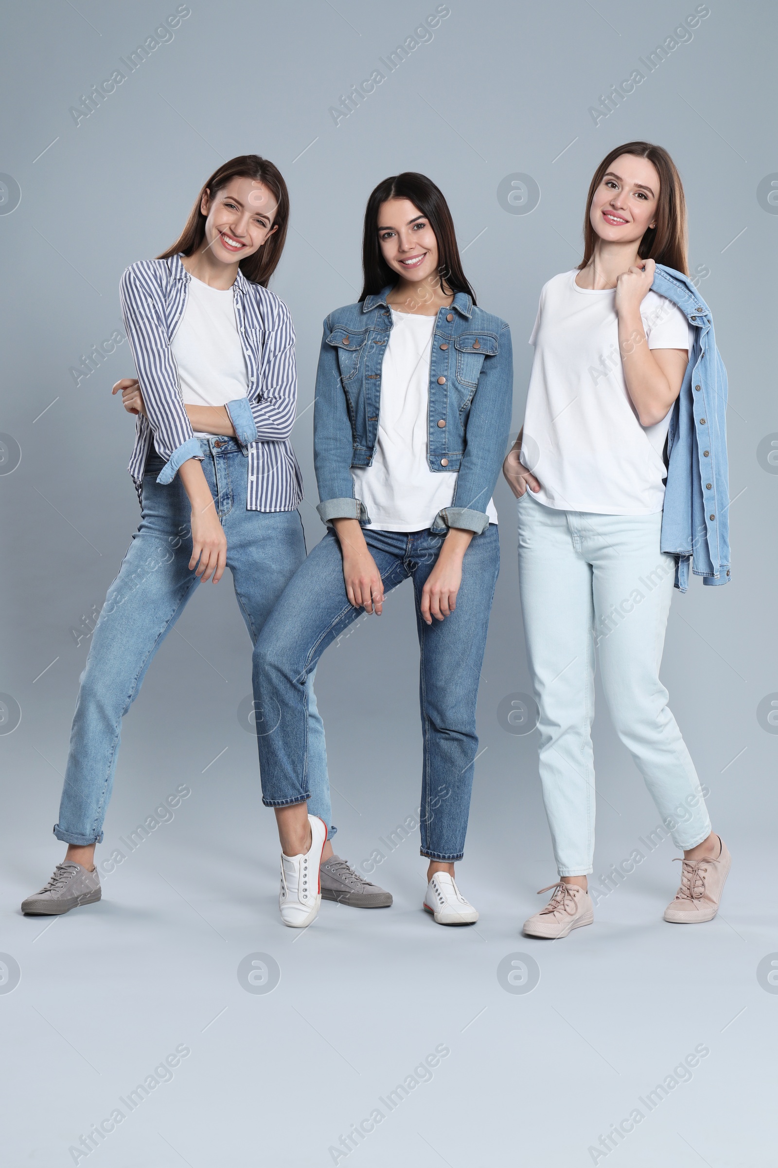 Photo of Group of young women in stylish jeans on grey background