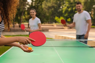 Friends playing ping pong outdoors, focus on hands