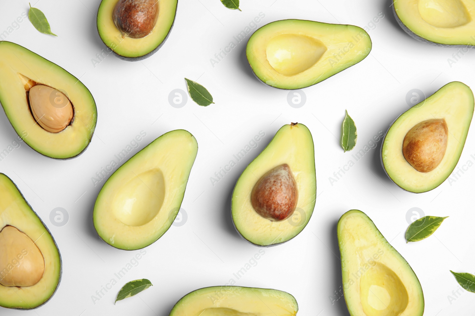 Photo of Cut fresh ripe avocados and leaves on white background, top view