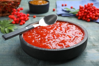 Photo of Delicious rowan jam in bowl on light blue wooden table