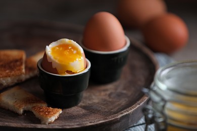 Soft boiled chicken eggs with toasted bread on wooden table, closeup