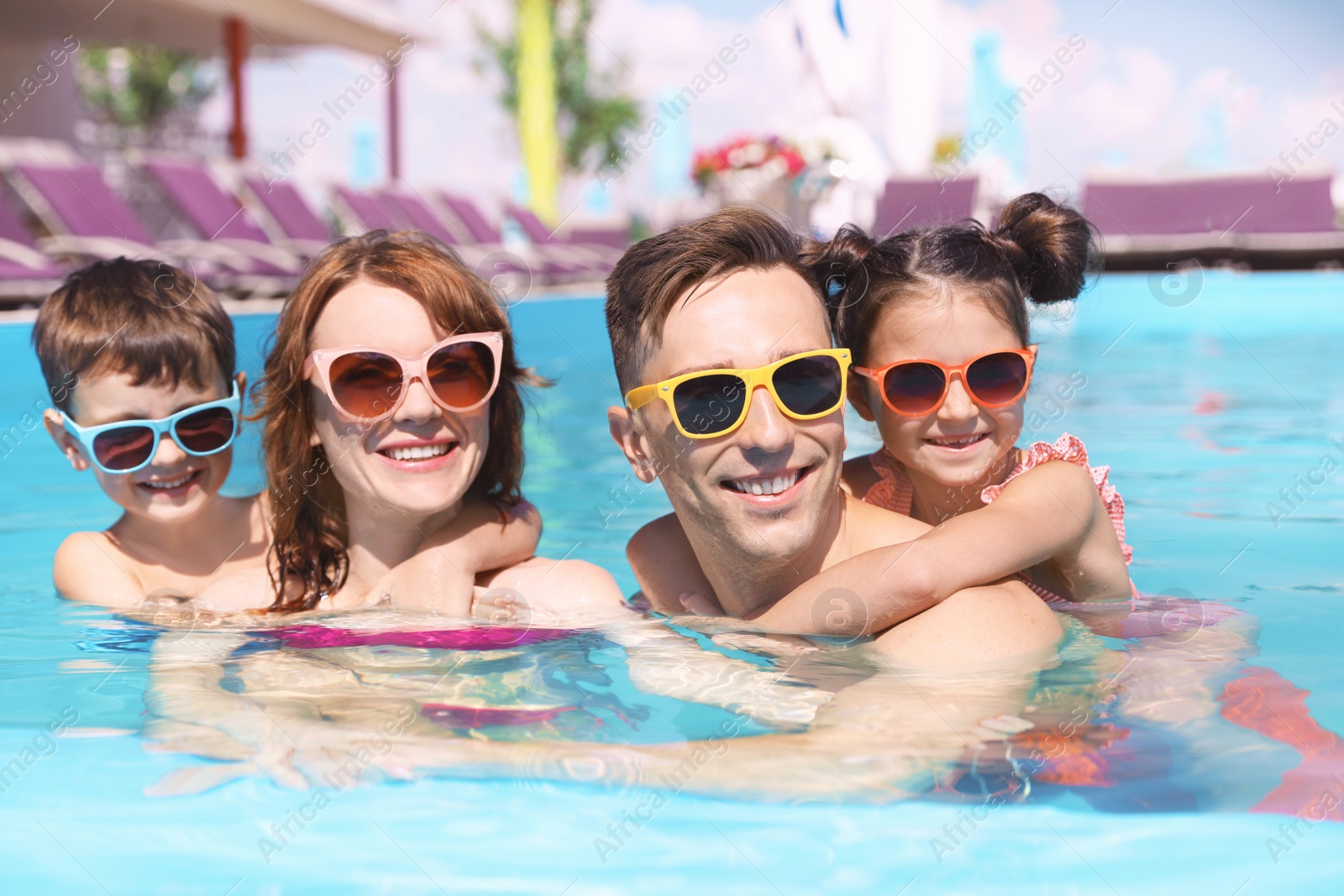 Photo of Happy family in swimming pool at resort