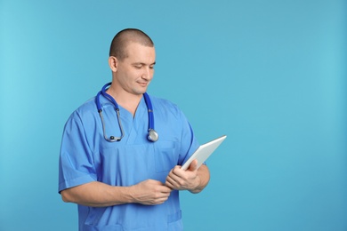 Portrait of medical assistant with stethoscope and tablet on color background. Space for text