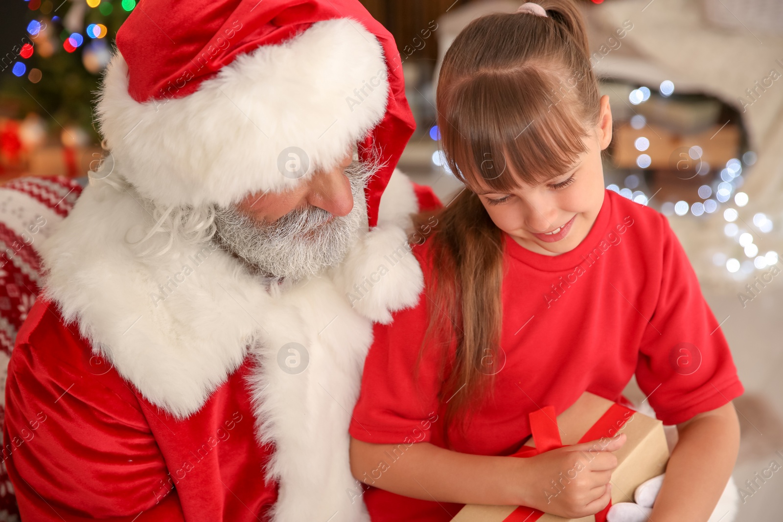 Photo of Little child with Santa Claus and Christmas gift at home