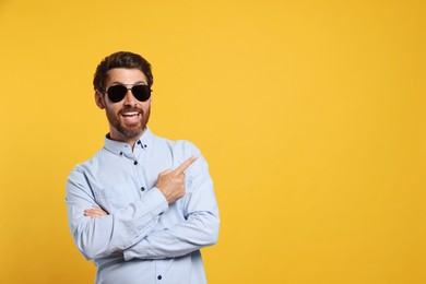 Photo of Portrait of excited bearded man with stylish sunglasses on orange background. Space for text