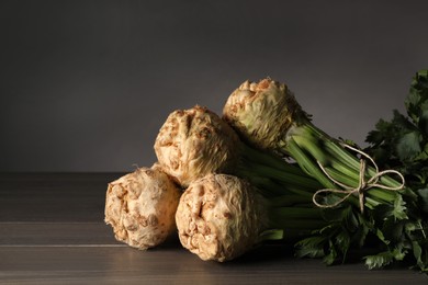 Photo of Fresh raw celery roots on wooden table. Space for text