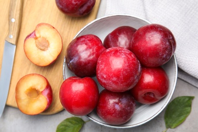 Delicious ripe plums on grey table, flat lay