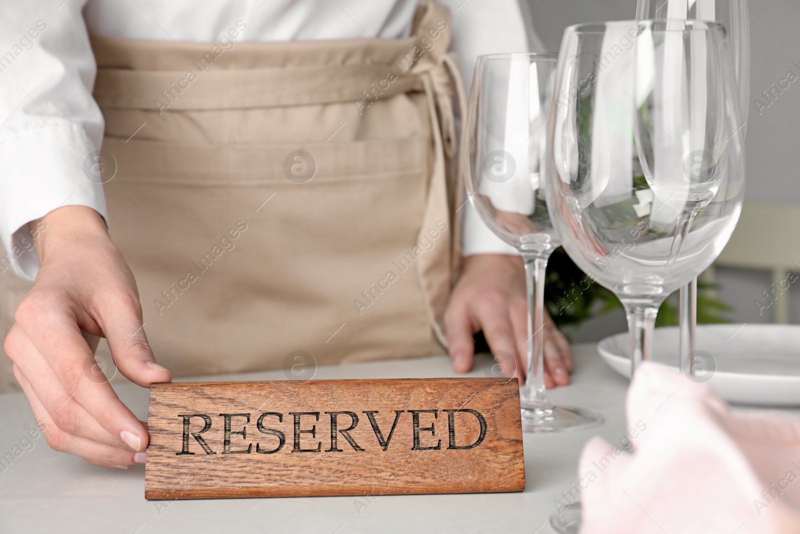 Photo of Waiter setting RESERVED sign on restaurant table, closeup