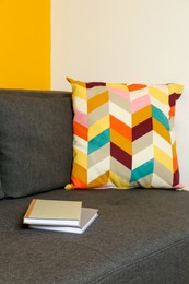 Photo of Bright cushion and books on grey sofa in room