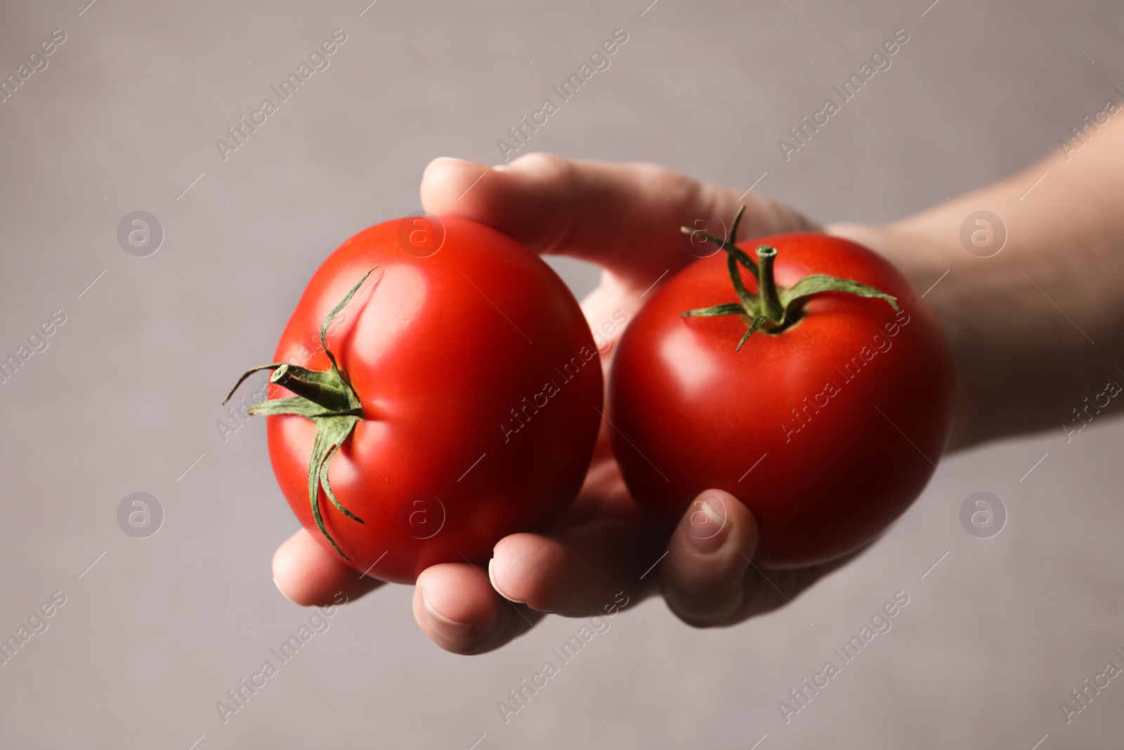 Photo of Woman with ripe tomatoes on grey background, closeup