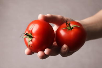 Woman with ripe tomatoes on grey background, closeup