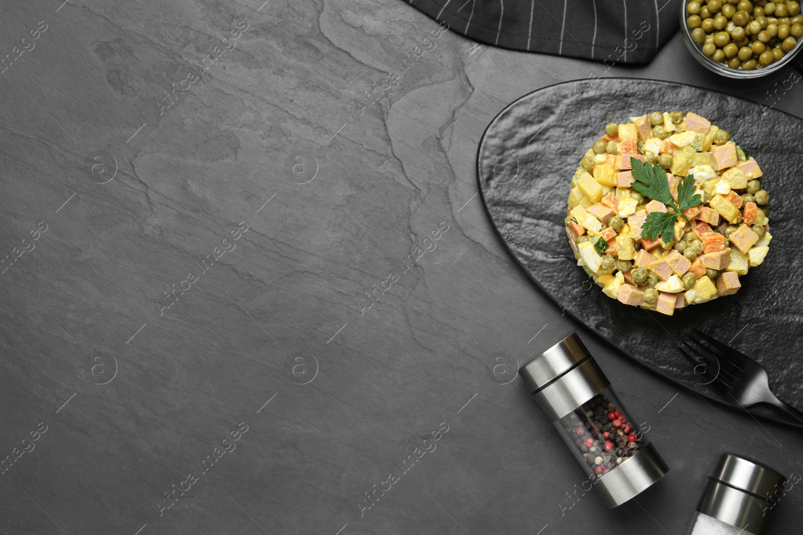 Photo of Delicious russian salad Olivier served on black table, flat lay with space for text