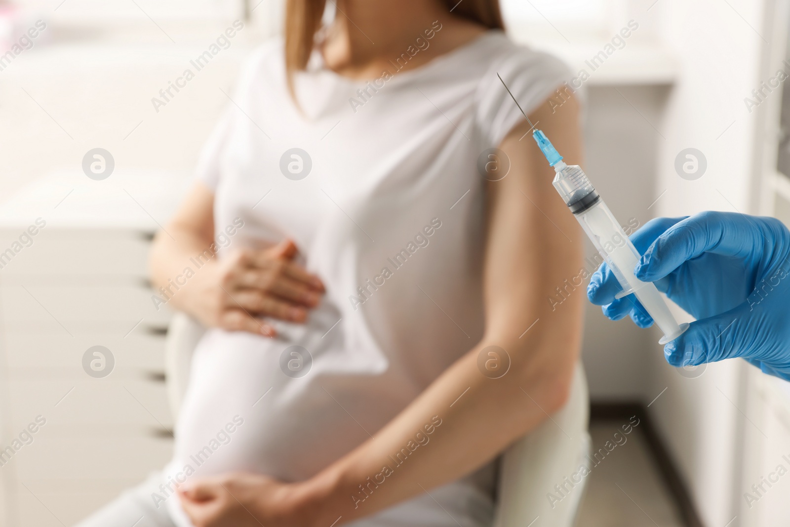 Photo of Doctor giving injection to pregnant woman in hospital, closeup