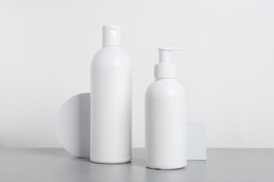 Photo of Bottles of cosmetic products on grey table